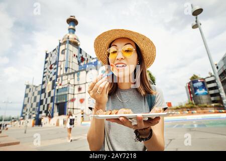 Happy asian woman degustazione austriaco deliziose salsicce wurst a Vienna Foto Stock