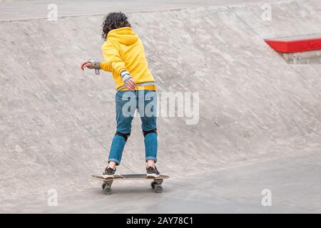 Ragazza che si diverte facendo trucchi e skateboard in un Parco specializzato Foto Stock