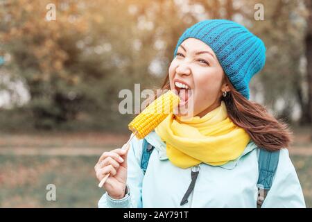 giovane donna che mangia mais bollito nel parco in autunno Foto Stock