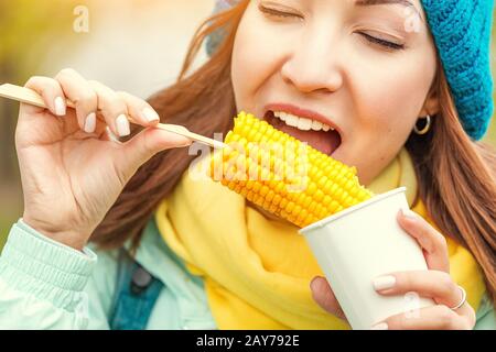 giovane donna che mangia mais bollito nel parco in autunno Foto Stock