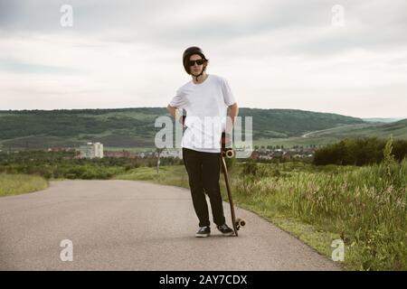 Un giovane ragazzo - uno skater in attesa di una gara su una strada di campagna Foto Stock