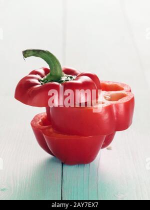 Peperoni rossi dolci tagliati su sfondo di legno blu Foto Stock