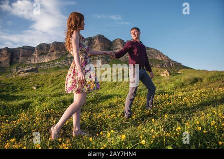 Giovane coppia sposata. Il ragazzo conduce una ragazza curly con un bouquet di fiori. Foto Stock