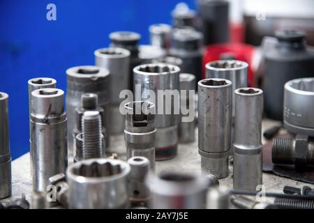 diversi bulloni e tasti finali del carburante su un banco di lavoro in un'officina del carburante. Foto Stock