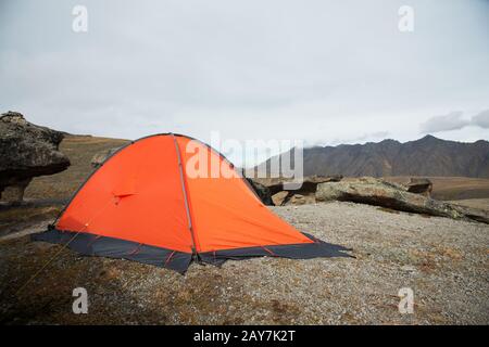 Una tenda arancione ad alta quota è posta in alta montagna sullo sfondo del crinale caucasico Foto Stock