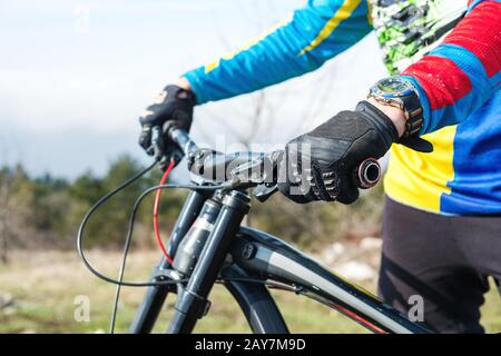 Primo piano di una mano uomo racer mtb ciclista in sport guanti pronti per una gara saldamente tiene il volante Foto Stock