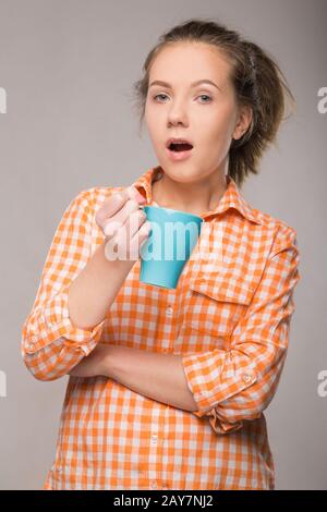 Studio ritratto di una donna addormentata in una maglietta arancione con una tazza Foto Stock