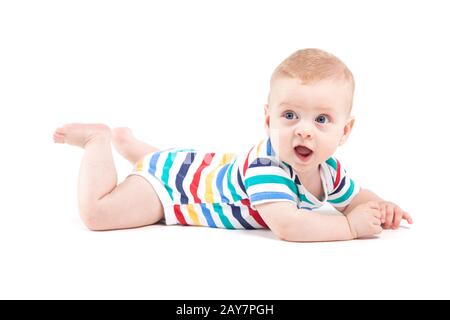 Carino stupiti little boy in colorate shirt giace sulla pancia Foto Stock