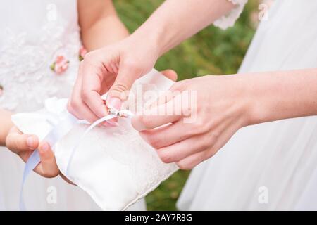 Primo piano mano bridesmaid in abito bianco prende con anelli di pastiglie. Foto Stock