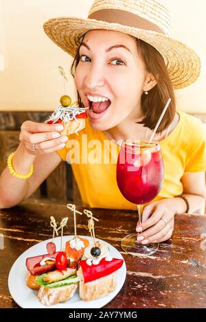 Giovane donna che gustava gustosi spuntini tradizionali spagnoli, con un bicchiere di vino sangria. Viaggi e cibo in Spagna concetto Foto Stock