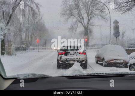 Un'auto è in piedi nella neve fioca davanti a barriere ferroviarie chiuse. Foto Stock