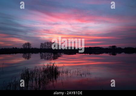 Nuvole colorate che si riflettono sul lago dopo il tramonto Foto Stock