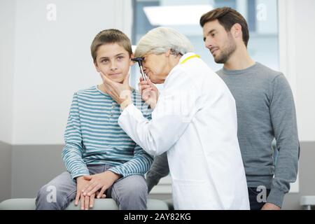 il medico femminile esamina l'orecchio del ragazzo con otoscopio Foto Stock