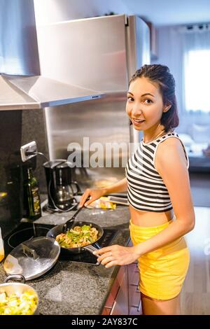 Donna cucina su cucina moderna a induzione fornello in cucina Foto Stock