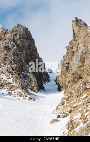 Primo piano. Vista di un couloir nevoso tra rocce taglienti. Foto Stock