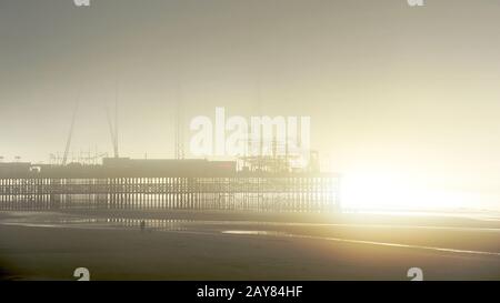 Molo sud in nebbia fitta in inverno con sole che si rompe attraverso, Blackpool, Regno Unito Foto Stock