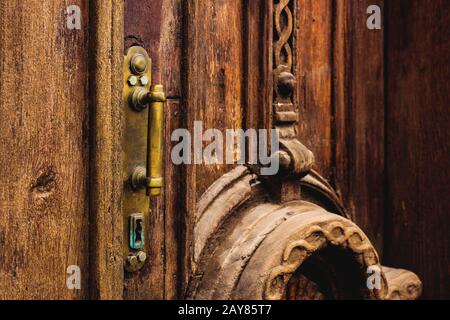 Sfondo vintage. Vecchia maniglia in ottone con elementi di una porta in legno intagliato decorata con massiccio tessuto in legno simulante Foto Stock