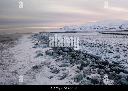 Vista aerea del ghiaccio e floes iceberg sulla spiaggia di diamante durante il tramonto. L'inizio della primavera in Islanda Foto Stock