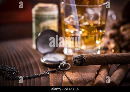 Glas con whiskey su cubetti di ghiaccio e sigaro cubano Foto Stock