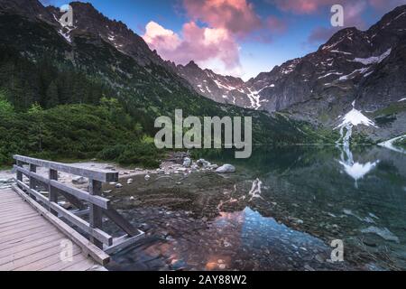 passerella in legno sulle montagne che si affacciano sul lago Foto Stock