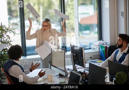 arrabbiato boss femminile gettare le carte di fronte a due dipendenti suprised. mobbing concetto Foto Stock