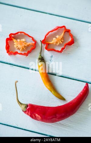 Sorridente viso divertente fatto con peperoncino caldo su legno Foto Stock