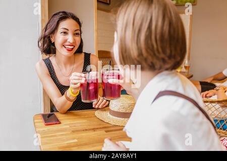 amici felici che graffiano il bicchiere dei cocktail sangria, bevande al bar Foto Stock