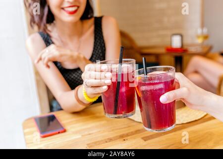 amici felici che graffiano il bicchiere dei cocktail sangria, bevande al bar Foto Stock