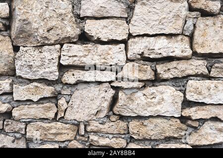 Primo piano sfondo testurizzato è un muro di pietra naturale irregolare fatto di pietre diverse senza una miscela di incollaggio tipo cemento. Foto Stock