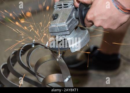 Scintille volanti durante la lavorazione del metallo con una smerigliatrice angolare - primo piano Foto Stock