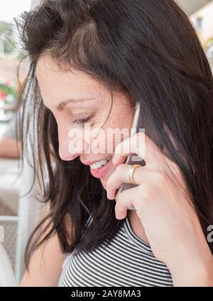 La ragazza brunetta con una t-shirt a righe parla sul telefono cellulare Foto Stock