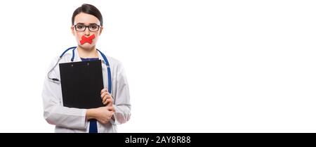 Giovane donna medico con stetoscopio negli appunti di contenimento nelle sue mani con labbra con nastro in divisa bianca su sfondo bianco Foto Stock