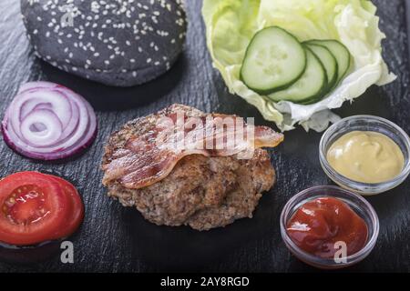 Ingredienti per un hamburger su ardesia nera Foto Stock