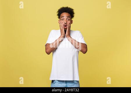 Concetto emotivo e Popolare - Ritratto di giovane africano eccitato americano uomo urlando in shock e stupore tenendo le mani su Foto Stock