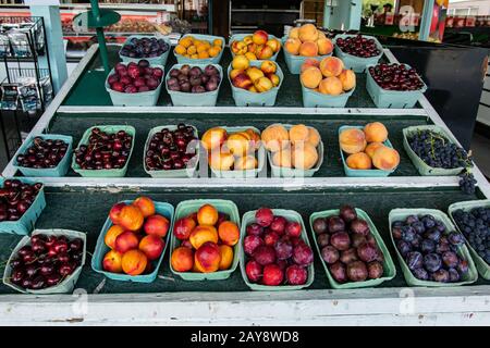 Primo piano di scatole di cartone verde ordinatamente organizzato di frutta mista colorata e lucida.mercato alimentare locale ambiente sullo sfondo. Varietà di scelta. Foto Stock
