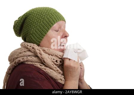 Una donna anziana nel tempo di inverno con la malattia deve starnutire e soffiare in un fazzoletto isolato su wh Foto Stock