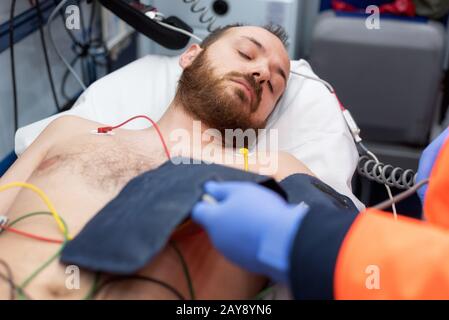 Medico di emergenza controllando la pressione del sangue di un paziente in ambulanza Foto Stock