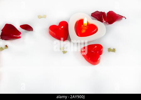San Valentino a forma di cuore candele e petali di rosa su sfondo bianco Foto Stock