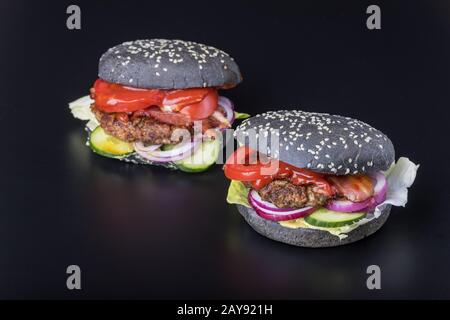 Primo piano di un hamburger nero su ardesia nera Foto Stock