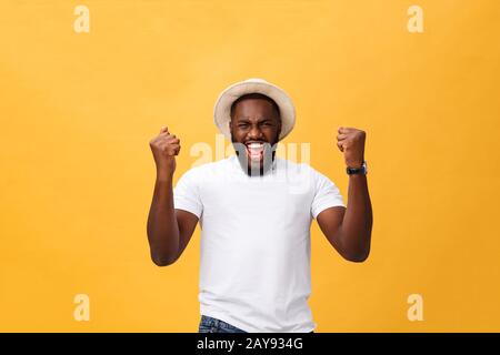 Bel giovane dipendente afro-americano si sente eccitato, gesturando attivamente, mantenendo i pugni stretti, esclamato con gioia Foto Stock