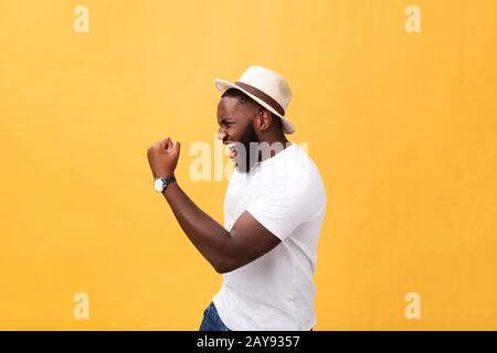 Bel giovane dipendente afro-americano si sente eccitato, gesturando attivamente, mantenendo i pugni stretti, esclamato con gioia Foto Stock