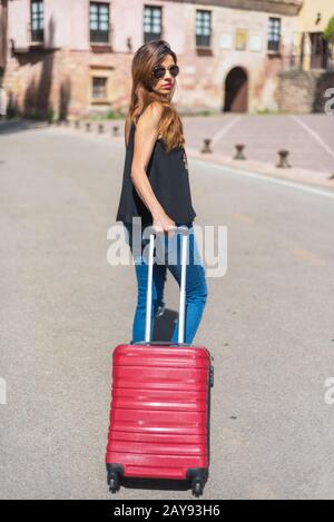 Lunghezza completa il ritratto di una donna che viaggia con il carrello. Focus su carrello. Foto Stock