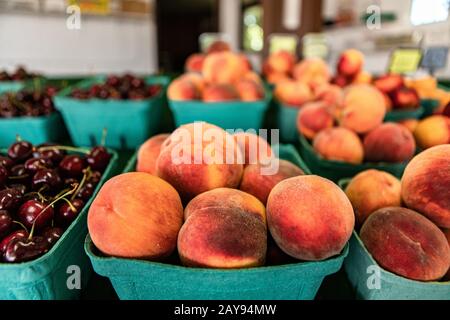 Chiudete le file ordinate di scatole di cartone verdi piene di pesche. Frutta fresca di pump in vendita al mercato locale. Messa a fuoco selettiva. Foto Stock