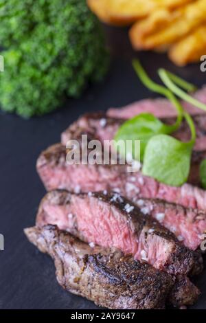 Fette di bistecca alla griglia su ardesia Foto Stock