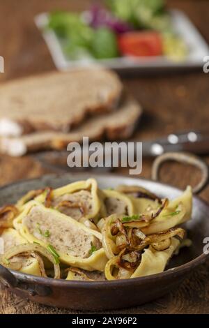 Swabian Maultaschen con cipolle in una padella Foto Stock