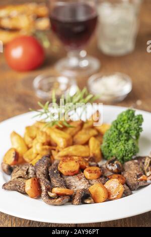 Fette di bistecca con carote e patatine fritte Foto Stock