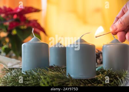 Persona luci prima candela sulla corona di Natale - primo piano Foto Stock