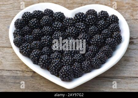 Bacche fresche mature giacciono su un piattino. cuore nero blackberry Foto Stock