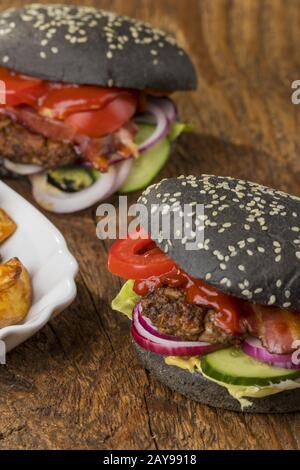 Primo piano degli hamburger neri su legno Foto Stock