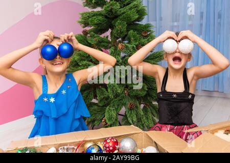 Due ragazze grandi palle di Natale ai loro occhi Foto Stock
